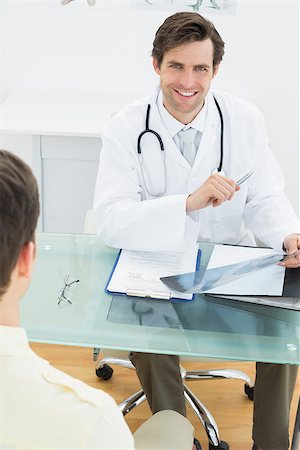 Portrait of a smiling doctor explaining x-ray reports to patient in the medical office Stockbilder - Microstock & Abonnement, Bildnummer: 400-07231996