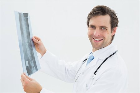 simsearch:400-05088212,k - Side view portrait of a male doctor examining spine x-ray over white background Stock Photo - Budget Royalty-Free & Subscription, Code: 400-07232004