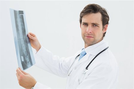 simsearch:400-07269250,k - Side view portrait of a male doctor examining spine x-ray over white background Stock Photo - Budget Royalty-Free & Subscription, Code: 400-07232003