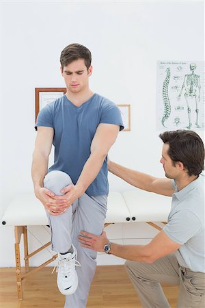 simsearch:400-07232187,k - Male therapist assisting young man with stretching exercises in the medical office Foto de stock - Royalty-Free Super Valor e Assinatura, Número: 400-07232032