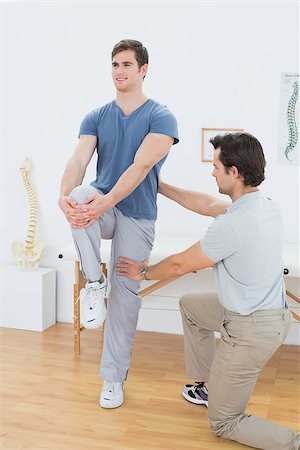 simsearch:400-07232187,k - Male therapist assisting young man with stretching exercises in the medical office Foto de stock - Royalty-Free Super Valor e Assinatura, Número: 400-07232033