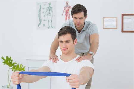 simsearch:400-07232187,k - Male therapist assisting young man with exercises in the medical office Foto de stock - Royalty-Free Super Valor e Assinatura, Número: 400-07232050