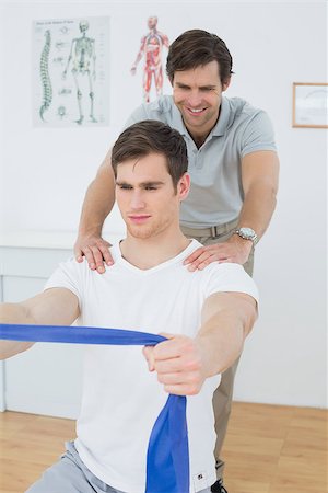 simsearch:400-07232187,k - Male therapist assisting young man with exercises in the medical office Foto de stock - Royalty-Free Super Valor e Assinatura, Número: 400-07232051