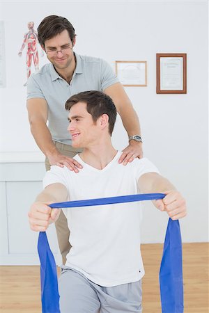 simsearch:400-07232187,k - Male therapist assisting young man with exercises in the medical office Foto de stock - Royalty-Free Super Valor e Assinatura, Número: 400-07232052