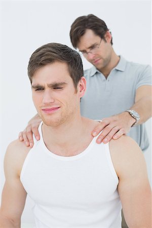 physical therapy shoulder - Male physiotherapist massaging a young mans shoulder over white background Stock Photo - Budget Royalty-Free & Subscription, Code: 400-07232077