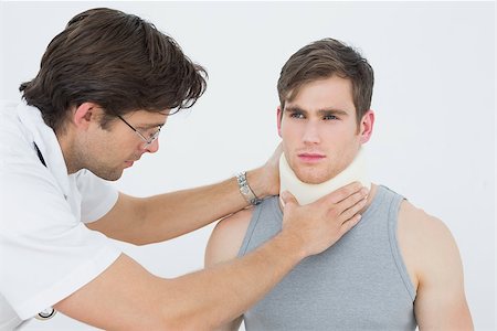 simsearch:400-07269643,k - Male doctor examining a patients neck over white background Fotografie stock - Microstock e Abbonamento, Codice: 400-07232114