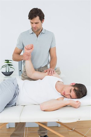 simsearch:400-04337005,k - Male physiotherapist examining a young mans hand in the medical office Foto de stock - Super Valor sin royalties y Suscripción, Código: 400-07232139