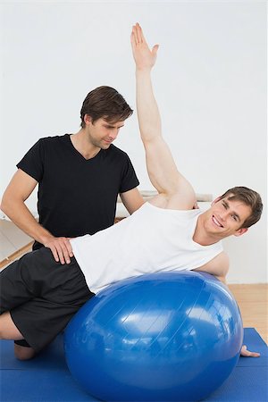 simsearch:400-07232187,k - Physical therapist assisting young man with yoga ball in the gym at hospital Foto de stock - Royalty-Free Super Valor e Assinatura, Número: 400-07232187