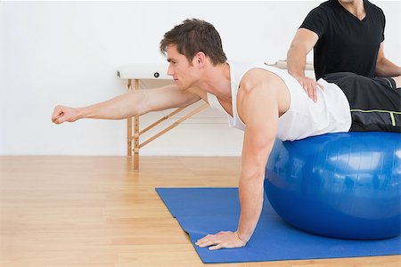 simsearch:400-07232187,k - Physical therapist assisting young man with yoga ball in the gym at hospital Foto de stock - Royalty-Free Super Valor e Assinatura, Número: 400-07232182