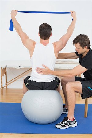 simsearch:400-07232187,k - Young man sitting on yoga ball while working with a physical therapist Foto de stock - Royalty-Free Super Valor e Assinatura, Número: 400-07232190