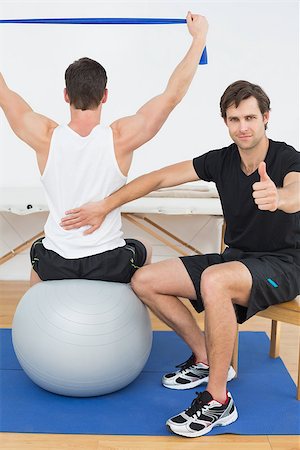 simsearch:400-07232187,k - Physical therapist gesturing thumbs up besides man on yoga ball Foto de stock - Royalty-Free Super Valor e Assinatura, Número: 400-07232191