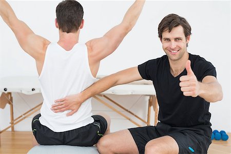 simsearch:400-07232187,k - Physical therapist gesturing thumbs up besides man on yoga ball Foto de stock - Royalty-Free Super Valor e Assinatura, Número: 400-07232192