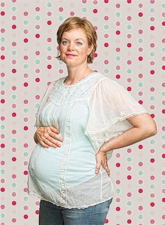 simsearch:400-05918412,k - Smiling pregnant woman on polka dot background Foto de stock - Royalty-Free Super Valor e Assinatura, Número: 400-07245516