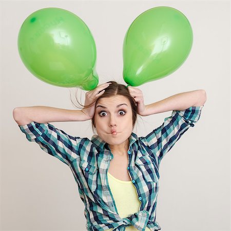 young woman playing with two green balloons making face studio shot Stock Photo - Budget Royalty-Free & Subscription, Code: 400-07247101