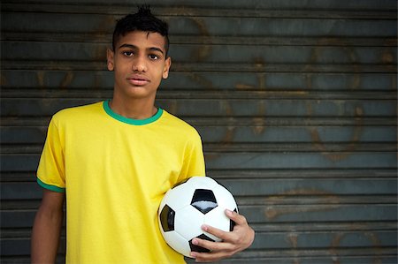 Portrait of young Brazilian soccer player holding football ball against rustic background Stock Photo - Budget Royalty-Free & Subscription, Code: 400-07254098