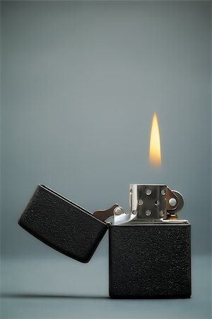 black gasoline lighter with flame on dark background Fotografie stock - Microstock e Abbonamento, Codice: 400-07254585