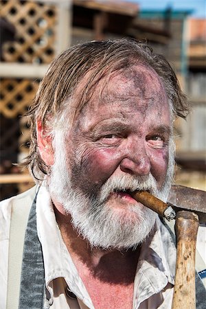 dirty overalls pictures - Old West Blacksmith Smokes Cigar While Holding Mallet Stock Photo - Budget Royalty-Free & Subscription, Code: 400-07256641