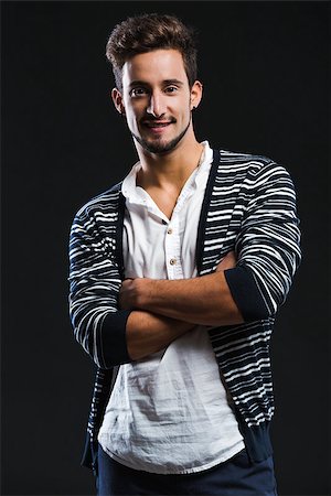 simsearch:400-05912369,k - Studio portrait of a fashion young man smiling, posing over a dark background Fotografie stock - Microstock e Abbonamento, Codice: 400-07252327