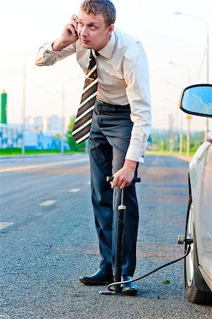 simsearch:400-07252682,k - businessman pumps the pump wheel of a car and talking on the phone Fotografie stock - Microstock e Abbonamento, Codice: 400-07252680