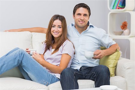 simsearch:6109-07601570,k - Portrait of a cute young couple sitting on sofa with tea cups at home Stockbilder - Microstock & Abonnement, Bildnummer: 400-07266786