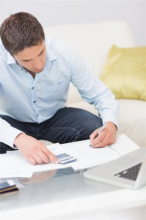 simsearch:400-07333928,k - Young man with bills, calculator and laptop in the living room at home Stock Photo - Budget Royalty-Free & Subscription, Code: 400-07266853