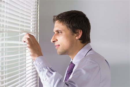 Side view of a young businessman peeking through blinds in the office Stock Photo - Budget Royalty-Free & Subscription, Code: 400-07266917