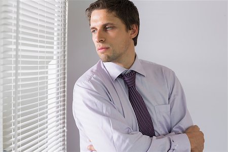 Serious young businessman peeking through blinds in the office Stock Photo - Budget Royalty-Free & Subscription, Code: 400-07266924