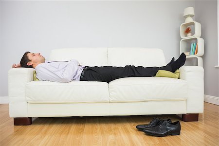 Side view of a tired young businessman sleeping on sofa in the living room at home Stock Photo - Budget Royalty-Free & Subscription, Code: 400-07266929