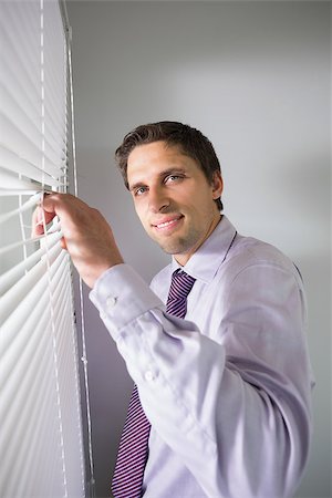 simsearch:400-07266908,k - Portrait of a young businessman peeking through blinds in the office Photographie de stock - Aubaine LD & Abonnement, Code: 400-07266921