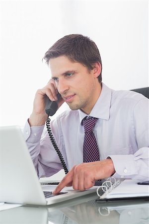 simsearch:400-07931035,k - Smiling businessman using telephone and laptop at office desk Stock Photo - Budget Royalty-Free & Subscription, Code: 400-07266941