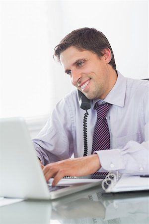 simsearch:400-07931035,k - Happy businessman using telephone and laptop at office desk Stock Photo - Budget Royalty-Free & Subscription, Code: 400-07266942