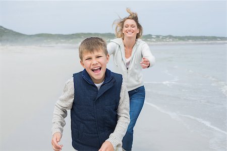 simsearch:400-07267308,k - Smiling young woman and cheerful boy running at the beach Fotografie stock - Microstock e Abbonamento, Codice: 400-07267265