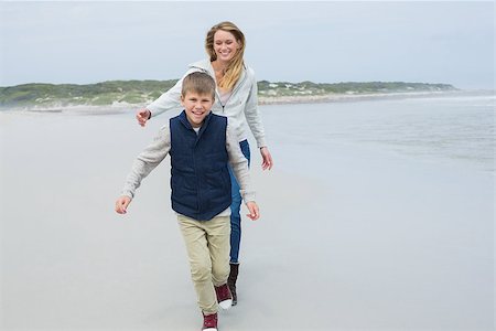 simsearch:400-07267308,k - Smiling young woman and cheerful boy running at the beach Fotografie stock - Microstock e Abbonamento, Codice: 400-07267263