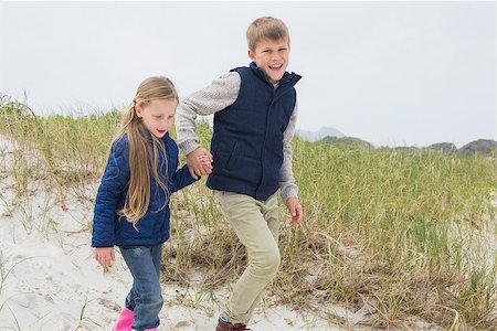 simsearch:400-07267308,k - Happy brother and sister walking hand in hand at the beach Fotografie stock - Microstock e Abbonamento, Codice: 400-07267285