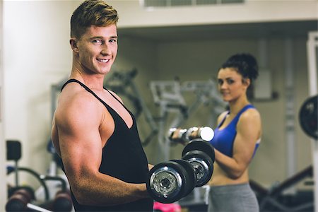 simsearch:400-06801591,k - Side view portrait of a young man and woman using dumbbells in the gym Stock Photo - Budget Royalty-Free & Subscription, Code: 400-07267321