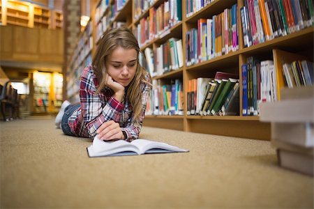 simsearch:400-07141917,k - Pretty focused student lying on library floor reading book in college Stock Photo - Budget Royalty-Free & Subscription, Code: 400-07267501