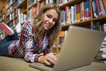 simsearch:400-07267769,k - Young smiling student lying on library floor using laptop in college Stock Photo - Budget Royalty-Free & Subscription, Code: 400-07267512