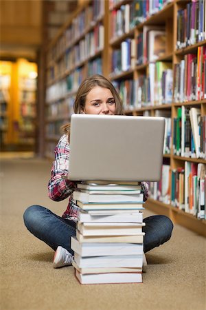 simsearch:400-07267769,k - Smiling student sitting on library floor using laptop on pile of books in college Stock Photo - Budget Royalty-Free & Subscription, Code: 400-07267537