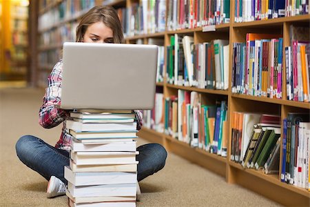 simsearch:400-07267769,k - Young student sitting on library floor using laptop on pile of books in college Stock Photo - Budget Royalty-Free & Subscription, Code: 400-07267533