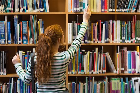 simsearch:400-07267769,k - Redhead student taking book from top shelf in library at the university Stock Photo - Budget Royalty-Free & Subscription, Code: 400-07267619