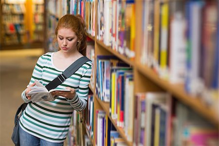simsearch:400-07267769,k - Redhead student reading book leaning on shelf in library at the university Stock Photo - Budget Royalty-Free & Subscription, Code: 400-07267628