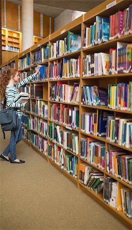 simsearch:400-07267769,k - Redhead student taking a book from bookshelf in the library at the university Stock Photo - Budget Royalty-Free & Subscription, Code: 400-07267658