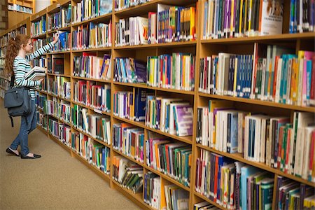 simsearch:400-07267769,k - Redhead student taking a book from library bookshelf at the university Stock Photo - Budget Royalty-Free & Subscription, Code: 400-07267660