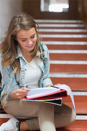 simsearch:400-07267769,k - Cheerful young student sitting on stairs reading notes in college Stock Photo - Budget Royalty-Free & Subscription, Code: 400-07267749