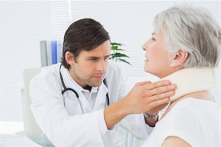 simsearch:400-07269643,k - Male doctor examining a senior patient's neck in the medical office Fotografie stock - Microstock e Abbonamento, Codice: 400-07267797