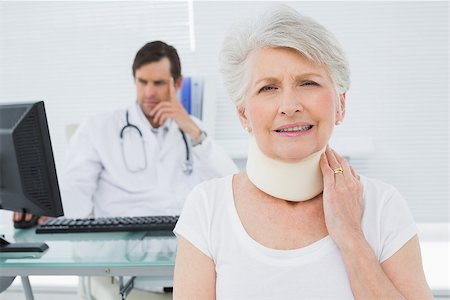 Senior patient in surgical collar with male doctor sitting at desk in background at medical office Stock Photo - Budget Royalty-Free & Subscription, Code: 400-07267799