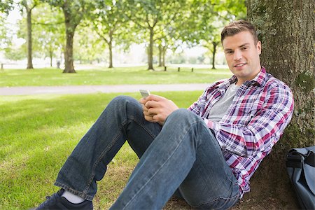 students campus phones - Cheerful student sending a text outside leaning on tree on college campus Stock Photo - Budget Royalty-Free & Subscription, Code: 400-07267802