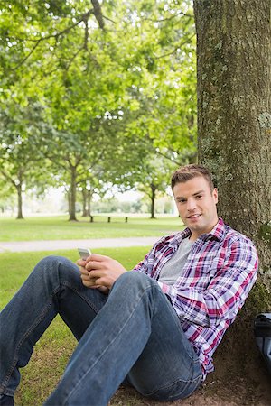 students campus phones - Happy student sending a text outside leaning on tree on college campus Stock Photo - Budget Royalty-Free & Subscription, Code: 400-07267803