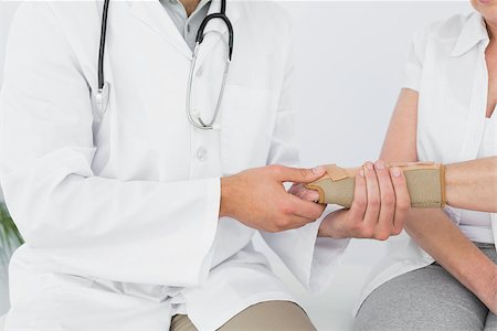 Close-up mid section of a male physiotherapist examining a woman's wrist in the medical office Stock Photo - Budget Royalty-Free & Subscription, Code: 400-07268241