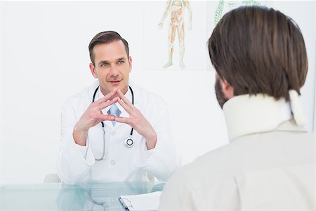 simsearch:400-07269643,k - Male doctor listening to patient with concentration at desk in medical office Fotografie stock - Microstock e Abbonamento, Codice: 400-07269159